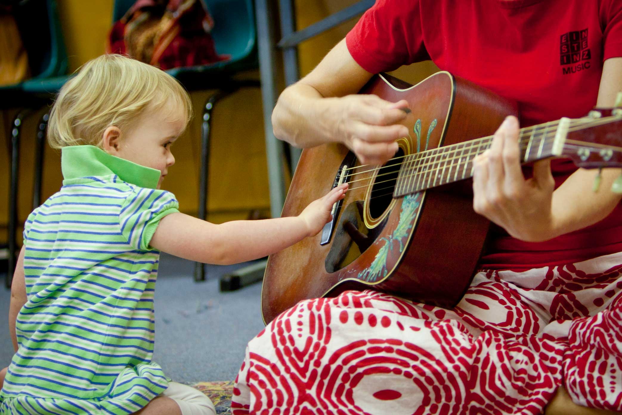 A toddler exploring a guitar in an Einsteinz Music class